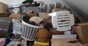 A room piled with boxes and an assortment of items. The walls are white, and there's a white outlet on it.