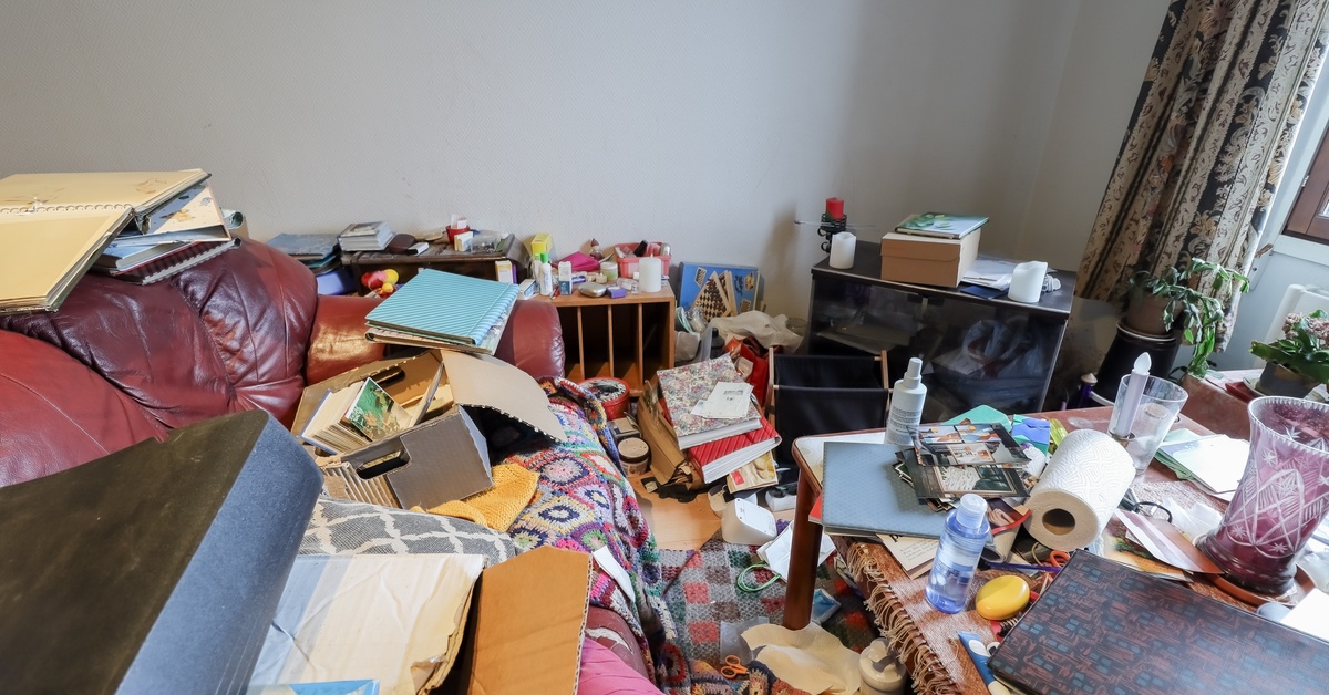 A hoarder's home, piled with items and scattered belongings all across the floor, table, and couch.